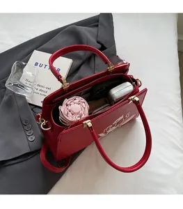 Interior view of red embroidered handbag showing large capacity and internal zipper pocket