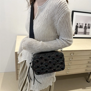 Fashionable black camera bag with rainbow stitching and wide strap worn by a model