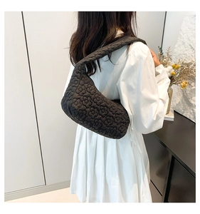 Detail of black quilted shoulder bag featuring 3D floral texture and puffy crescent design