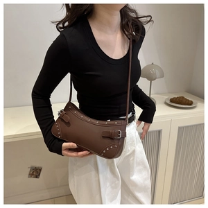 Dettaglio borsa a mezzaluna in pelle marrone opaca con rivetti metallici e cinturini