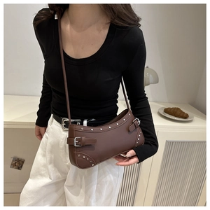 Detail of a brown leather shoulder bag with silver rivets and metal buckle strap design