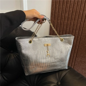 Detailed close-up of a silver crocodile pattern tote bag with a golden deer charm pendant