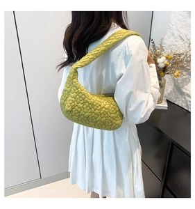 Close-up of quilted floral texture on a light green puffy hobo bag worn by a model