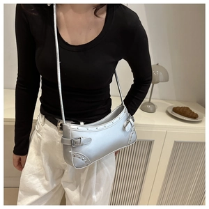 Detail of silver metallic rivet baguette bag with belt buckle on a minimalist counter