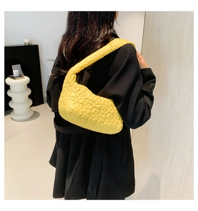 Detail of yellow quilted shoulder bag with 3D floral texture and crescent shape