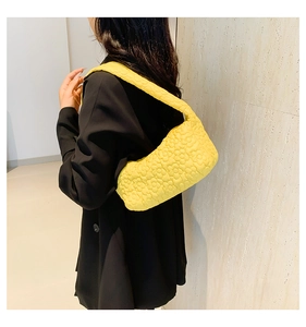 Detail of bright yellow quilted underarm bag featuring 3D floral textures and wide strap