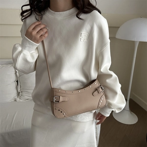 Beige retro underarm bag with metal studs and adjustable strap shown on shoulder