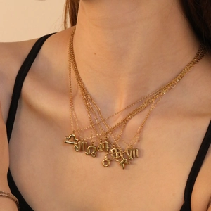 Close-up of layered 18K gold zodiac pendants featuring Libra and Leo bubble designs