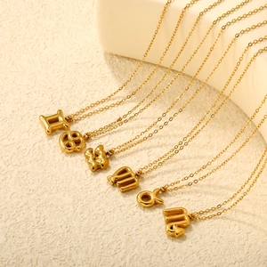 Detail of 18K gold zodiac bubble pendants including Gemini and Cancer on delicate chains