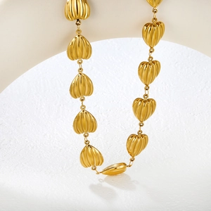 Makroaufnahme der goldenen Edelstahlkette mit strukturierten hohlen Herzanhängern