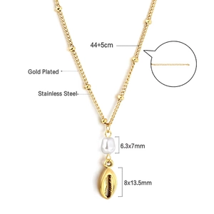 Detalle de una cadena de acero inoxidable dorado con perla de agua dulce y dije de caracola