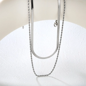 Détail de colliers superposés en argent avec maille serpent et corde sur support