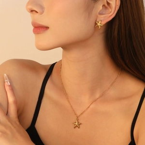 Golden starfish pendant necklace and earrings set worn by a female model in warm light