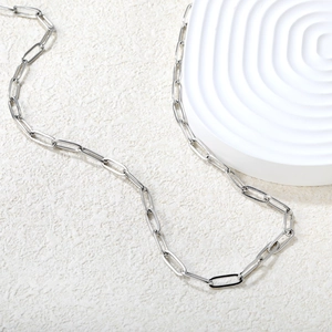 Vue détaillée d'un collier chaîne trombone en argent poli sur un socle en pierre