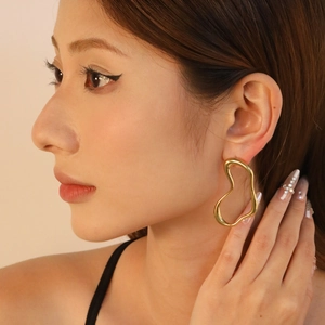 Boucles d'oreilles créoles cœur irrégulier plaqué or 18 carats portées par un mannequin