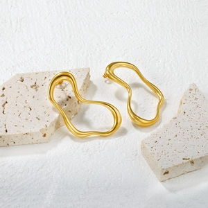 Boucles d'oreilles géométriques dorées irrégulières sur support en pierre blanche texturée