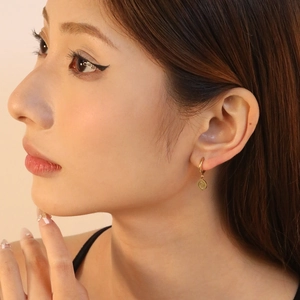 Détail de la boucle d'oreille disque spirale plaquée or 18K portée par un mannequin