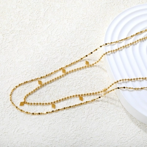 Detalle del collar de doble capa chapado en oro de 18K con dijes de rombo y cuentas