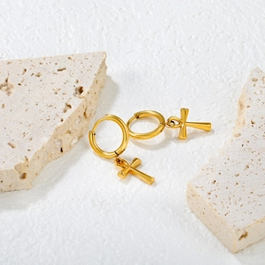 Polished gold stainless steel hoop earrings with Ankh cross pendants on stone background