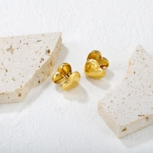 Polished gold heart hoop earrings in stainless steel on stone background