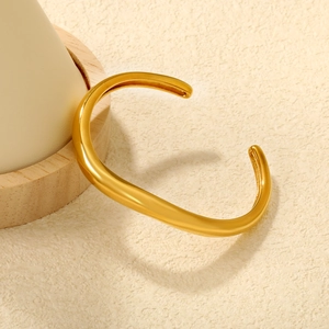 Irregular C-shaped curved open bracelet in 18K gold plated stainless steel on wooden base
