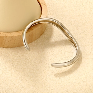 Macro shot of minimalist silver curved open cuff bangle with high-polished mirror finish
