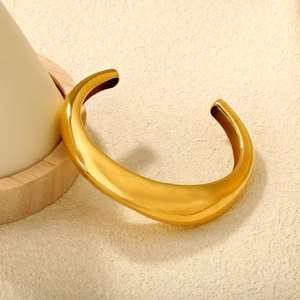 Irregular C-shaped gold-plated open bangle with a polished mirror finish and thick design