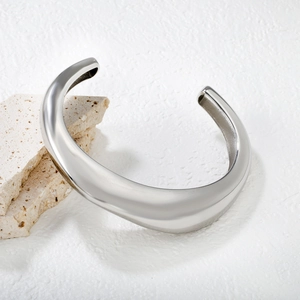 Macro view of wide silver irregular C-shape bangle showing high-polished mirror finish