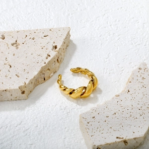 Bague ouverte torsadée en or évidée de style minimaliste sur fond de pierre texturée