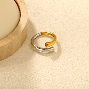 Detail of minimalist two-tone gold and silver irregular spiral ring on aesthetic surface