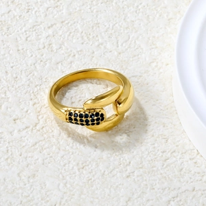 Nahaufnahme eines vergoldeten Crossover-Rings mit blauen Zirkonia auf weißem Grund