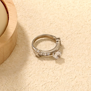 Détail d'une bague argentée avec design latéral en X et pierres de zircon scintillantes