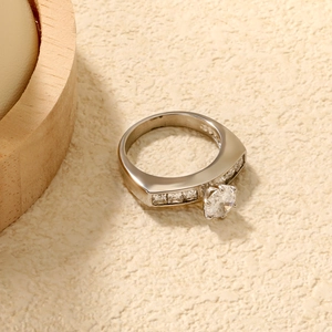 Makroaufnahme eines silberfarbenen Rings mit rundem Solitärdiamanten und Kanalfassung