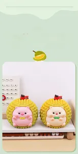 Detail view of pink pig and yellow hamster figurines inside durian shells on desk