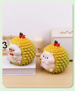 Close-up of creative cat and durian money bank ornaments in two sizes on a desk