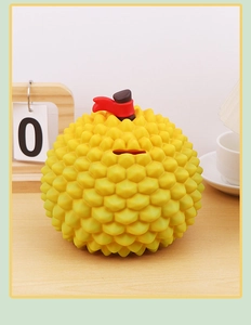 Detailed close-up of realistic yellow durian piggy bank with textured surface on wooden desk
