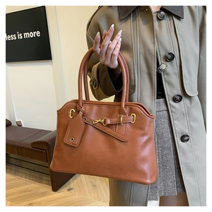 Gros plan détaillé du sac Boston marron avec texture cuir lisse et détails dorés brillants