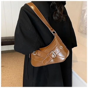 Détail du sac sous le bras en cuir caramel avec boucle en métal sur un manteau noir