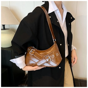 Détail du sac sous le bras vintage caramel avec boucles et œillets métalliques argentés
