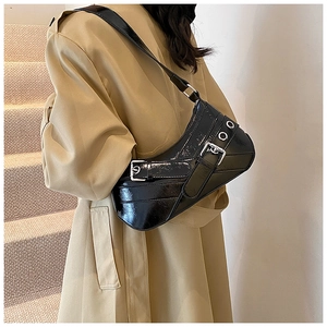 Détail d'un sac d'épaule en cuir verni noir avec boucles argentées et œillets punk
