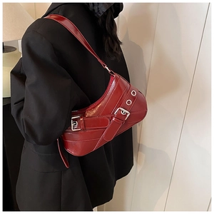 Détail du sac d'épaule en cuir verni rouge avec boucle et œillets métalliques