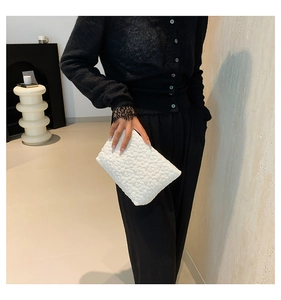 Close-up of white quilted flower texture on a soft minimalist handbag held by a model