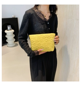 Detailed view of bright yellow clutch with 3D floral quilted pattern and glossy fabric