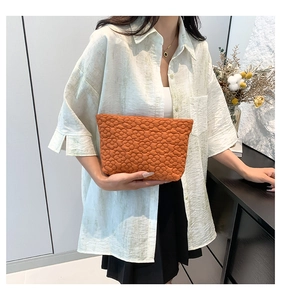 Detail of an orange pleated flower handbag showing the unique quilted texture and fabric