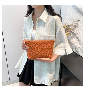 Close-up of orange quilted floral texture clutch bag with soft padded fabric detail