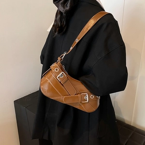 Sac croissant caramel avec boucles argentées porté par un mannequin en blazer noir