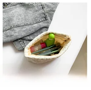 Detail showing white quilted wavy makeup bag interior with cosmetics for capacity display