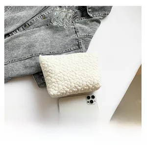 White quilted floral cosmetic bag shown with a smartphone for precise size comparison
