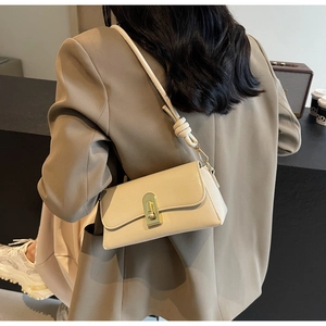 Détail du sac à bandoulière en similicuir crème avec fermoir doré sur blazer