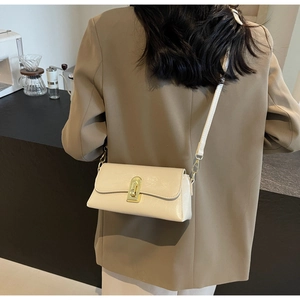 Détail d'un sac à bandoulière crème en similicuir avec un fermoir rotatif en métal doré
